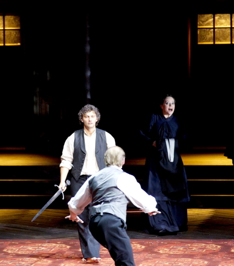 Jonas Kaufmann (Lohengrin)-Evelyn Herlitzius (Ortrud) i Tómas Tómasson (Telramund) en el acte 1er de Lohengrin a la Scala de Milà 2012. Producció Claus Guth Foto Handout